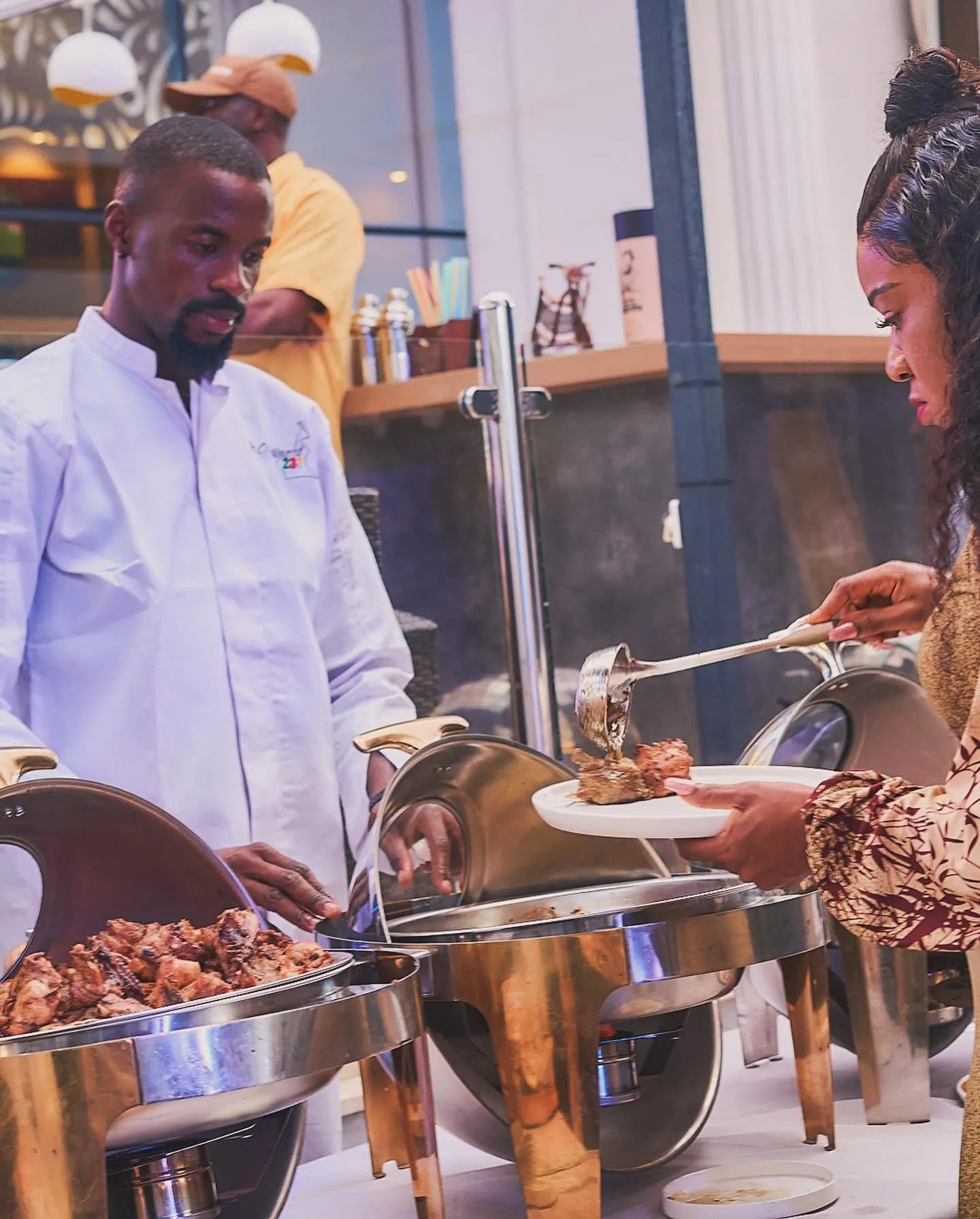 Le chef au buffet devant les morceaux de poulet grillé, une cliente se sert en sauce
