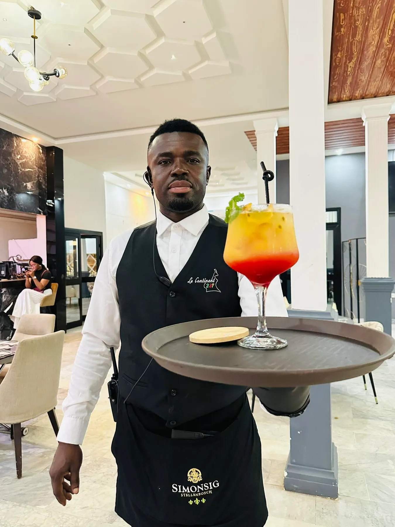 Serveur présentant un cocktail passion et grenadine en dégradé