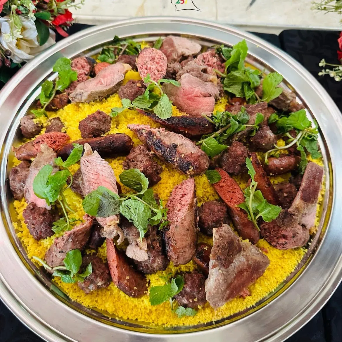 Grillades mixtes sur couscous jaune : agneau rosé, merguez, boulettes et menthe fraîche